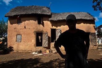 Portrait of a man belonging to the Betsileo ethnic group, standing in front of his house,