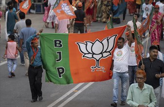 Bharatiya Janata Party (BJP) supporters holds a BJP flag as they arrives to to see a roadshow of