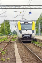 Commuter train entering a railway station in the summer