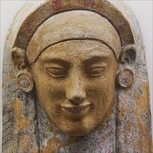 Female terracotta bust, A coloured stone relief of an ancient face with detailed facial features,