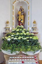 Side altar with Marian figure, floral decoration and sacrificial candles, Kronburg branch church,