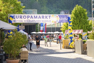 A lively European market with lots of people and colourful stalls in the city centre in sunny