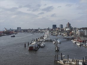 View of a busy river harbour with boats and city background on a cloudy day, many ships in a