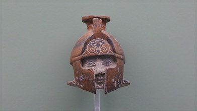 Aryballos, Ceramic vessel, Ancient sculpture of a helmet with a human face in front, brown against