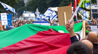 Protesters of the Al Quds demonstration with a large Palestinian flag march past the pro-Israel