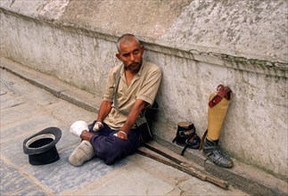 Leper waiting for alms, amputated man with foot and leg prostheses, Kathmandu, Nepal, Asia