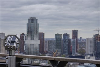 City view with binoculars in the foreground and modern skyscrapers in the background under a grey