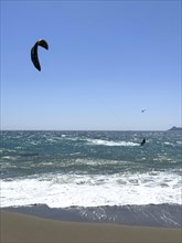 Kitesurfer kite surfer surfing in strong wind and waves rough sea choppy sea with inflated sail,