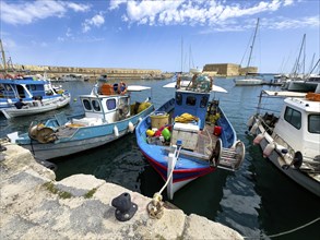 Several small fishing boats in historic Venetian harbour of Heraklion, left in the background