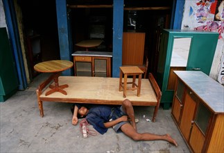 Young man sleeping on the ground in the shop where he is working, Kathmandu, Nepal, Asia