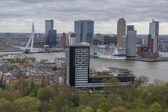 City view with prominent skyscraper skyline, river, cruise ship and modern bridge under a cloudy
