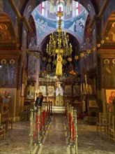 Tourist visiting sanctuary interior of orthodox church with in background chandelier chandelier