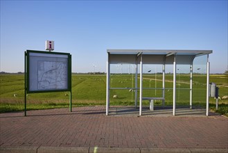 Glass bus shelter at a bus stop and information with road map in the marshland near Simonsberg,