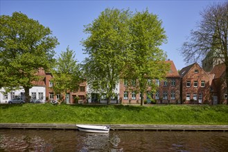 Motorboat on the Mittelburggraben with trees and houses in Friedrichstadt, district of