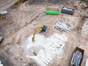 Aerial view of a construction site with an excavator, demolished material and containers on a