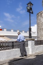 Senior citizen looking over a parapet on the street, Vejer, Andalusia, Spain, Europe