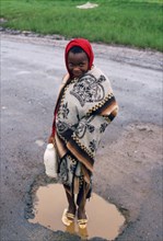 Girl washing her shoes in a puddle, rainy day in Lesotho, girl from the Basotho ethnic group,