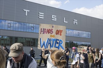 Participant with sign Hands off our water in front of the Tesla Gigafactory at the demonstration