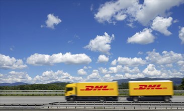 A DHL lorry drives past Deggendorf on the A3 motorway, with the Bavarian Forest in the background,