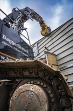 Close-up of an excavator with a steel chain demolishing a building, demolition, Saarbruecken,