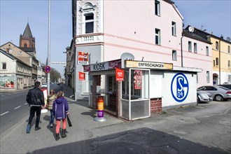 A pedestrian walks past a kiosk in Gelsenkirchen with a large S04 logo of FC Schalke 04 on it,