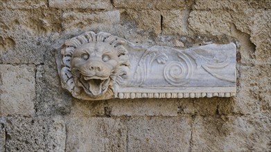 Ancient stone relief of a lion's head, carved into a wall, rich in details and textures, outdoor