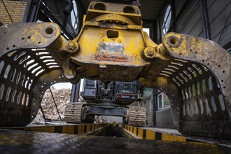 Close-up of an excavator with grab arm carrying out demolition work in a building, demolition,