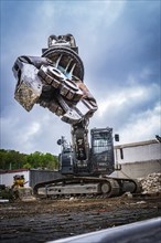Large excavator with gigantic demolition tongs in the air on a construction site, surrounded by