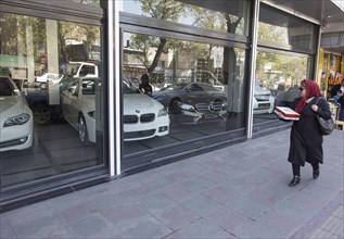 A woman walks past a car dealership with BMW and Mercedes cars in Tehran on 07/04/2015, Tehran,