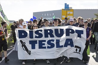 Participants with banner Disrupt Tesla in front of the Tesla Gigafactory at the demonstration Water