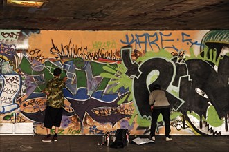 Graffiti artist at work in a skateboard park on the Thames, London, England, Great Britain