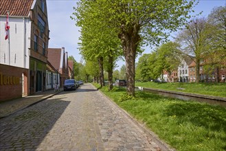 Cobbled street with trees and houses along the Mittelburggraben in Friedrichstadt, Nordfriesland