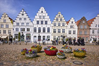 Flower baskets and historic houses with gables on the market square in Friedrichstadt,