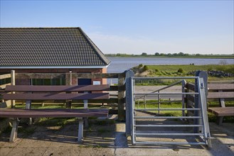 Self-closing door and bench on the dyke crest near Tetenbuell, Nordfriesland district,