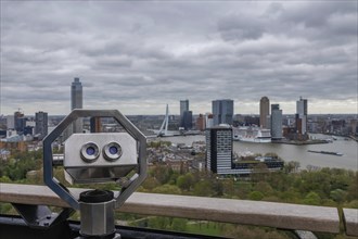 View with binoculars in the foreground and a city with skyscrapers and river in the background,