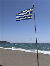 National flag of Greece waving on beach on south coast of Crete island on Mediterranean Sea,