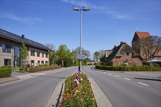Street with central island, lantern and buildings in Niebuell, Nordfriesland district,