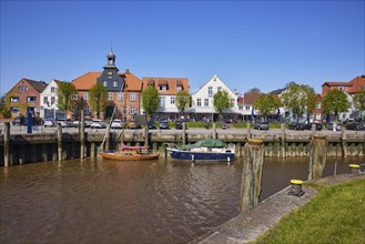 Row of houses with skipper's house, trees and boats in Toenning harbour, Nordfriesland district,