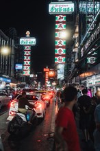 Street signs illuminated at night with Chinese characters light up the crowded streets of Chinatown