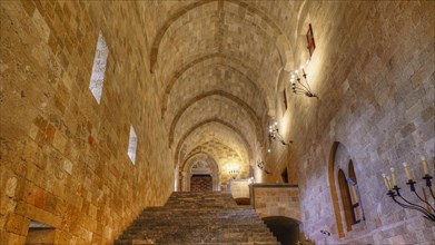 An illuminated corridor with vaulted ceiling and stone stairs in an old fortress, interior view,