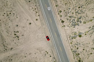 Drone shot of Route 66 with Route 66 sign on the road and red Ford Mustang convertible, Mojave