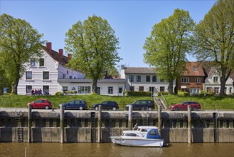 Houses, trees and harbour basin with motorboat in Toenning harbour, Nordfriesland district,