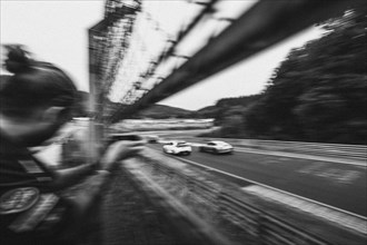 Monochrome shot of racing cars from the perspective of a spectator with motion blur. Nuerburgring