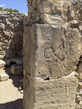 Sign carved in stone former wall symbol graffiti In archaeological site on hill of Phaistos of