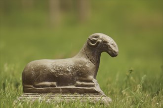 Ceramic sculpture of a ram, motif cropped, meadow background KI generated, Antique stone sculpture