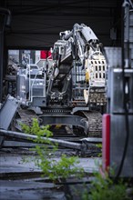 An excavator in a building surrounding plants and rubble, demolition, Saarbruecken, Germany, Europe