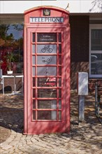 Public e-bike charging station in an old, red English telephone box on the town hall square in