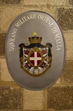Emblem of the Sovereign Order of Malta on a stone wall, interior view, Grand Master's Palace,