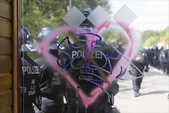 Police officers stand behind a spray-painted heart at a bus stop during the Wasser. Forest. Justice