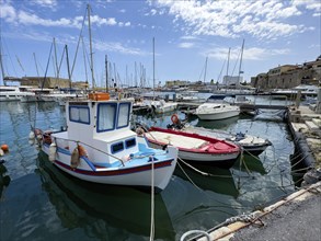 Several small fishing boats in historic Venetian harbour of Heraklion, left in the background